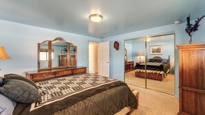 Ein Schlafzimmer mit einem großen Bett, einem Schminktisch, einem Spiegel und einer Tür zu einem weiteren Raum.