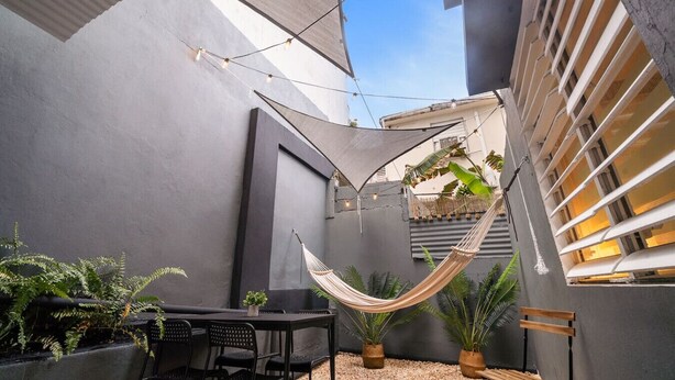 Un patio exterior moderno con una hamaca, asientos y plantas en macetas.