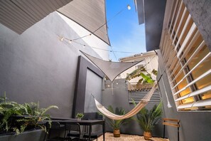 A modern outdoor patio with a hammock, seating, and potted plants.