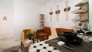Una sala moderna con un sofá, una mesa de comedor con platos negros y adornos colgantes en la pared.