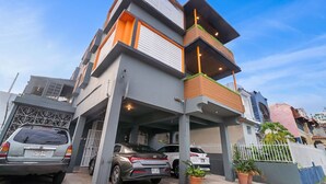 Una casa moderna de dos pisos con garaje, coches aparcados y una valla blanca.