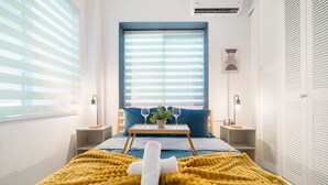 Un dormitorio moderno con cama, mesita de noche, ventana con persianas y armario.