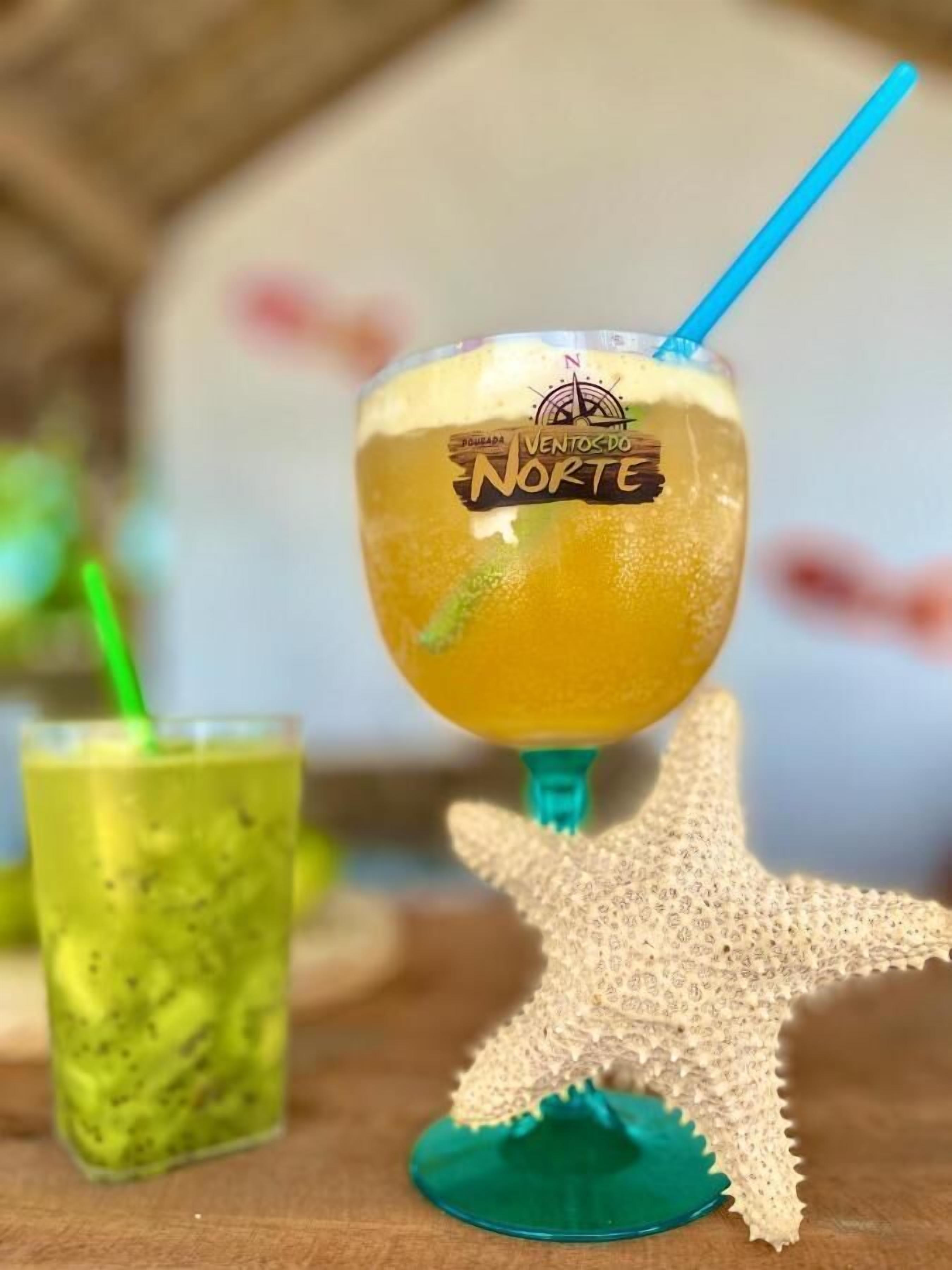 A cocktail glass with a blue straw and a label that reads "VENTOS DO NORTE".