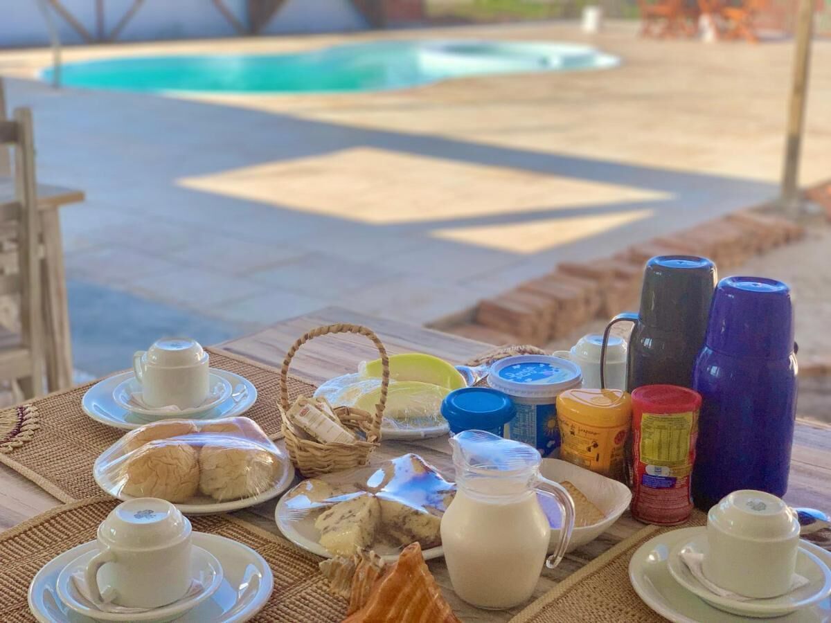 Desayuno con diferentes alimentos y recipientes sobre una mesa cerca de una piscina.