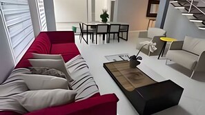 Una sala de estar moderna con un sofá rojo, una mesa de centro y un comedor al fondo.