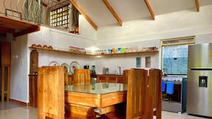 Una cocina con una mesa de comedor de madera, sillas y un refrigerador de acero inoxidable.