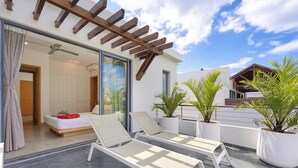 A modern hotel room with a balcony, a bed, and two lounge chairs. - Penthouse Blue Horizon, 5 min Mont Choisy beach (Trou-aux-Biches)