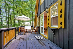 A wooden deck with a checkered mat, two wooden chairs, and a table.