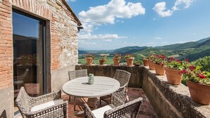 A patio with wicker furniture, a round table, and terracotta pots with flowers. - VILLA SOVRANA - Ten Bedroom Villa, Sleeps 20 (Perugia)