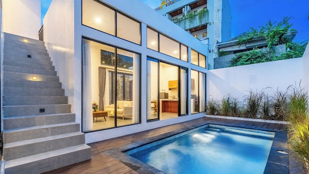 A modern house with a swimming pool, wooden deck, and large windows. -  Light Way Villa in Canggu (Canggu)