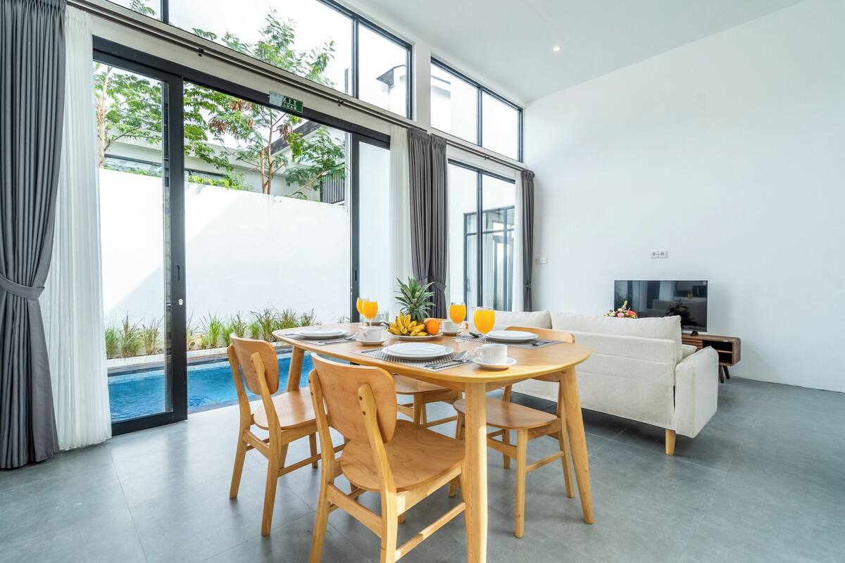 A modern living room with a dining area, a pool, and a sofa.