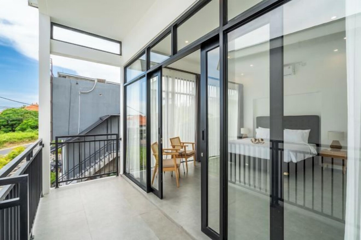 Un balcon moderne avec des portes vitrées, un lit et un coin repas.