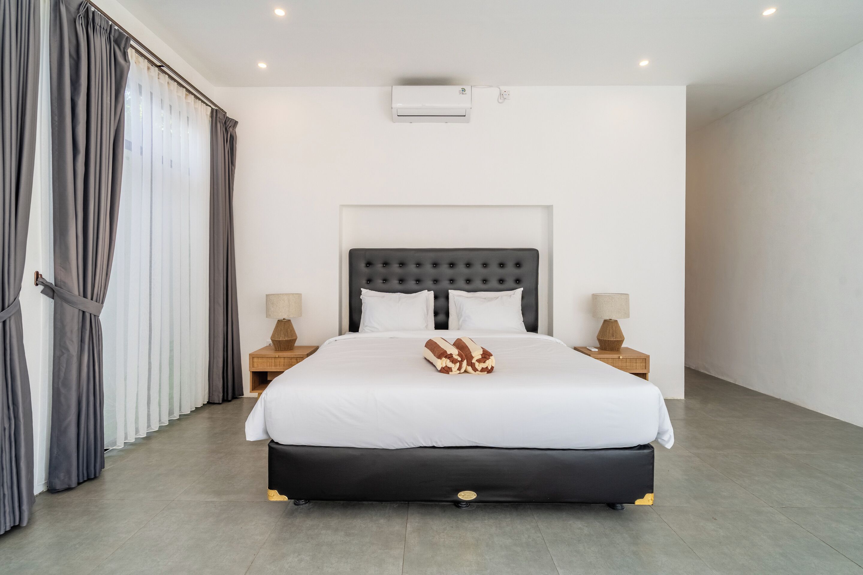 A modern hotel room with a large bed, two bedside tables, and a headboard.