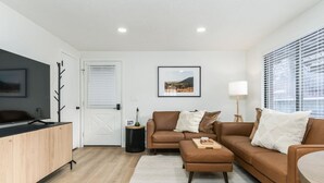 Een moderne woonkamer met een bruine leren bank, een houten kast en een flatscreen televisie.