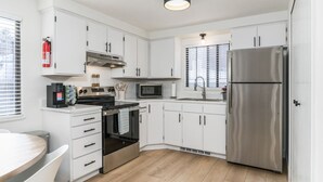 Een moderne keuken met witte kastjes, roestvrijstalen apparatuur, een inbouwoven, magnetron en koelkast.