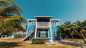 A two-story house with a balcony, a staircase, and a view of the ocean.