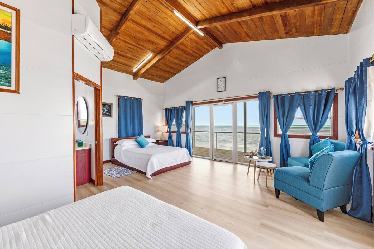 Ein Schlafzimmer mit einem Bett, einem Schlafsofa, einem kleinen Tisch und Blick aufs Meer.
