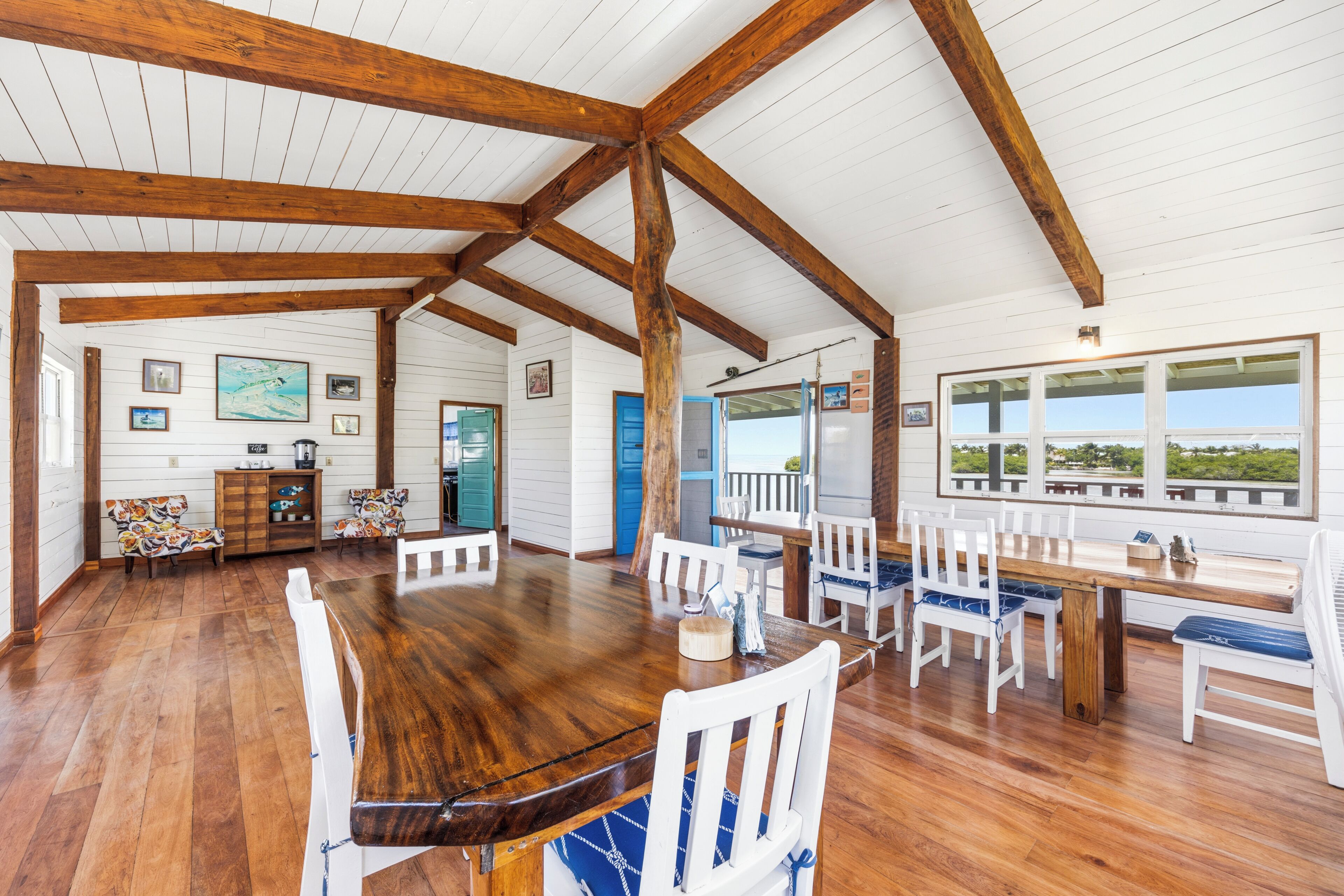 A spacious dining area with a wooden table and chairs, a wooden ceiling, and a view through large windows.