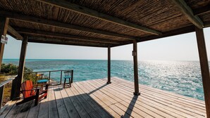 A wooden deck with a view of the ocean, a covered area with a 'No Smoking' sign, and two chairs.