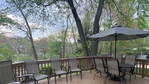 An outdoor deck with wooden flooring, metal chairs, and a table with an umbrella. - Comfortable home in Alexandria, walkable to Old Town / Metro, close to DC (Alexandria)