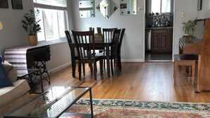 A spacious living room with a large wooden dining table, a glass coffee table, and a patterned rug. - Comfortable home in Alexandria, walkable to Old Town / Metro, close to DC (Alexandria)