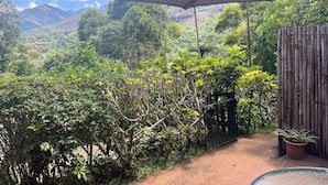 Un balcón con vistas a exuberante follaje y montañas lejanas.