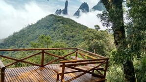 Una terraza de madera con barandilla que da a una montaña boscosa.