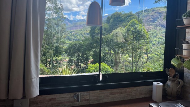 Una cocina con un ventanal grande que da a un paisaje verde exuberante y montañas.