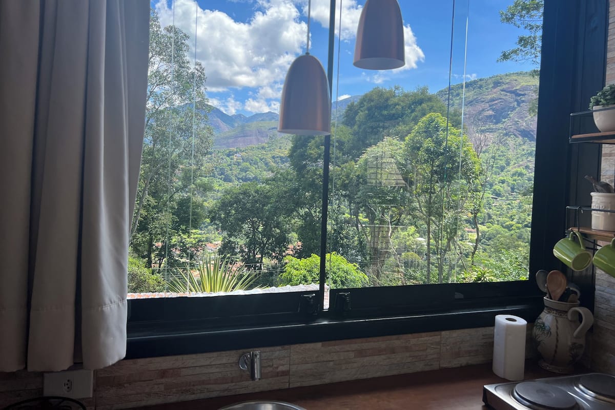 Eine Küche mit großem Fenster mit Blick auf eine üppige grüne Landschaft und Berge.