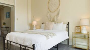 A bedroom with a bed, bedside lamps, a wall hanging, and a small table with a lamp.