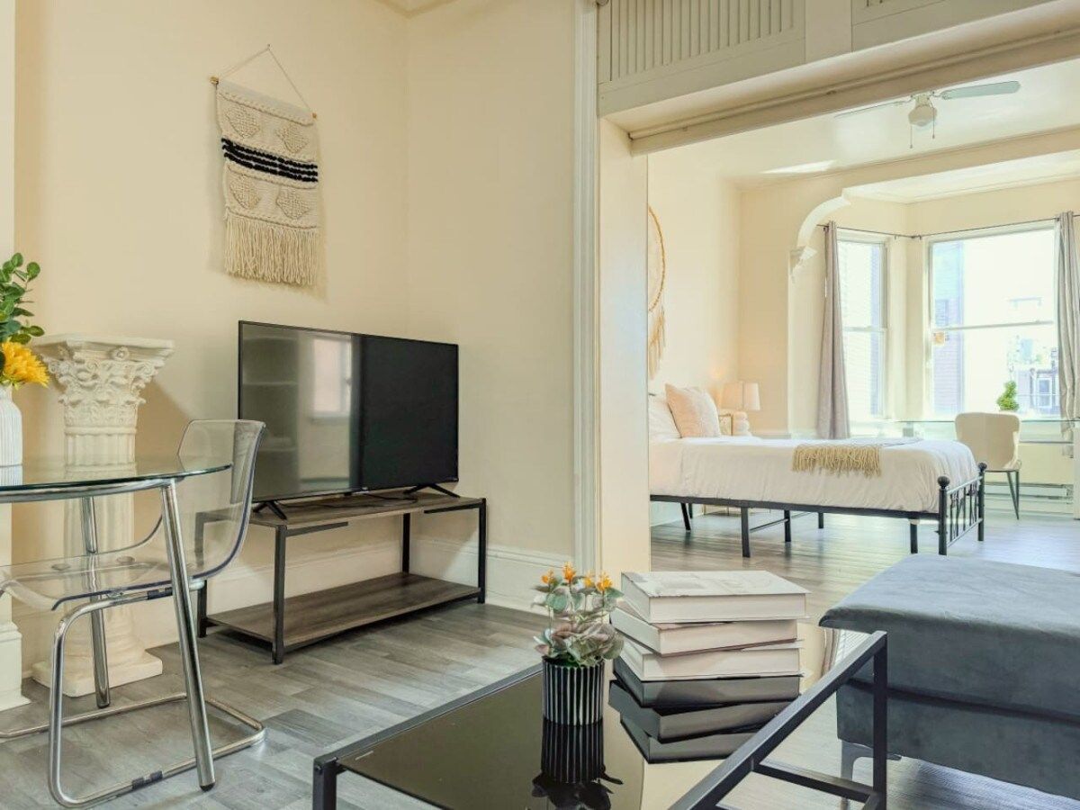 Ein modernes Wohnzimmer mit Glastisch, Flachbildfernseher und einer Couch.