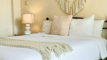 Un lit bien fait, avec du linge de lit blanc et un plaid beige.