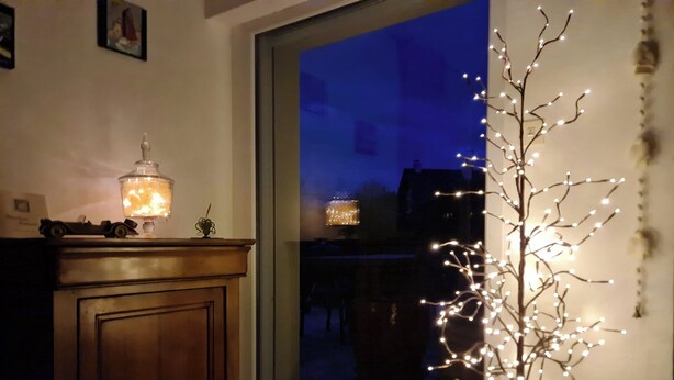 Ett rum med ett träskåp, en tänd lampa och ett fönster med utsikt över omgivningen.
