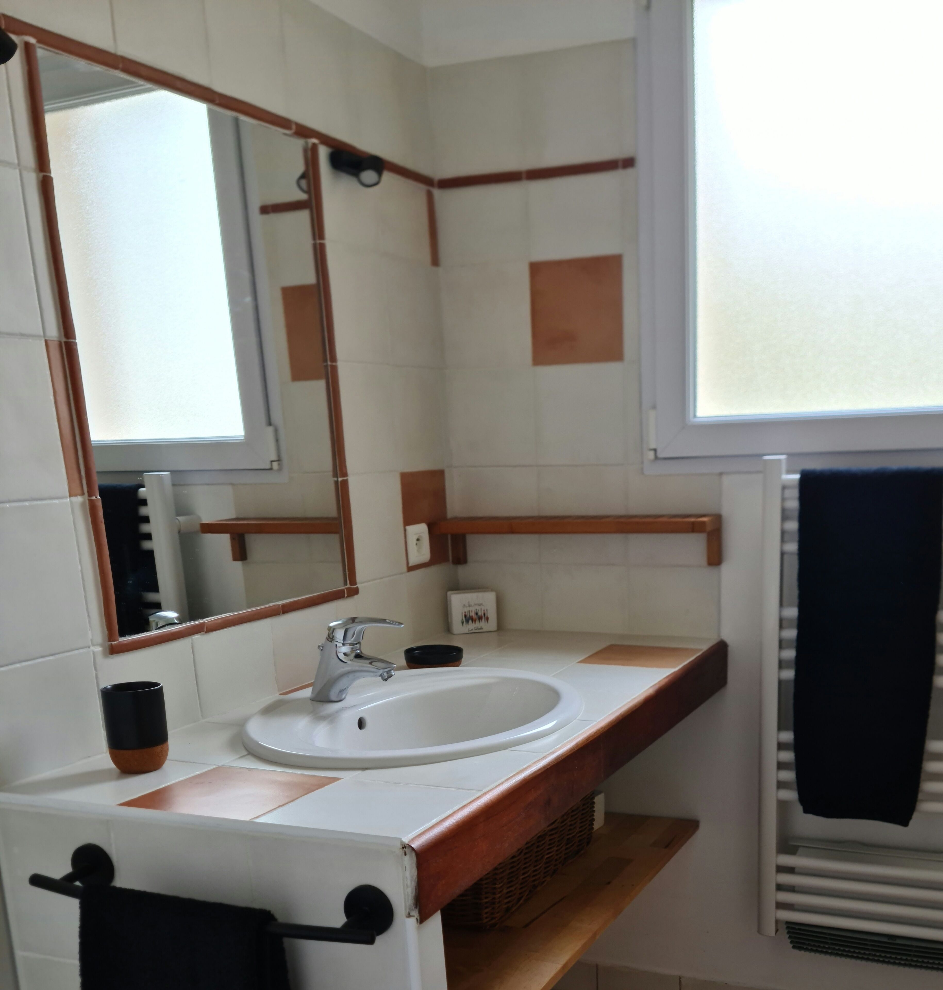 Een badkamer met een witte wastafel, een spiegel en een handdoekrek.