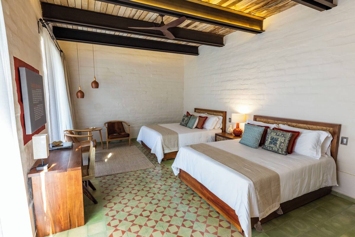 Habitación de hotel con dos camas, un escritorio y una silla.
