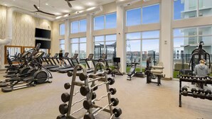 Un gimnasio amplio con cintas de correr, máquinas de pesas y un estante con mancuernas.
