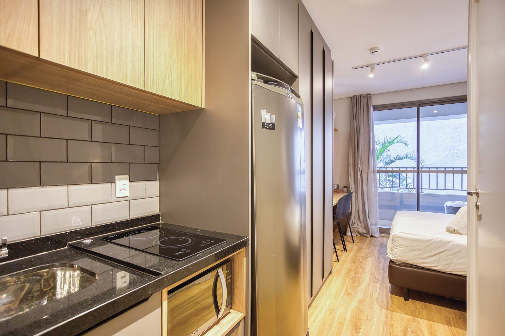 Une chambre d’hôtel compacte comprenant un coin cuisine, un lit et un balcon avec vue.
