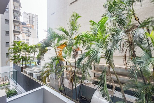 A rooftop garden with palm trees and a view of high-rise buildings. - 360 Horizon Paraíso (Sao Paulo)