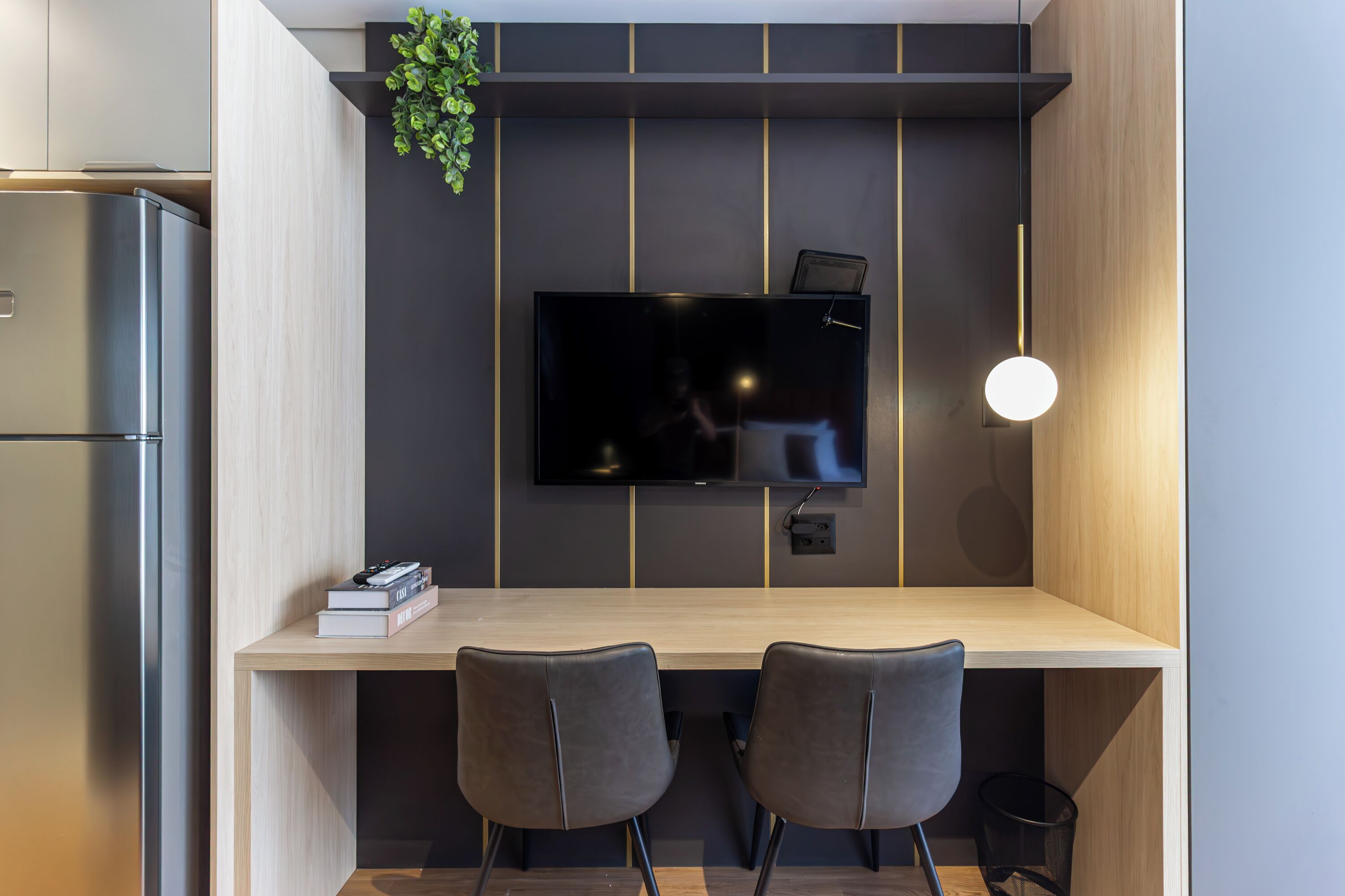A modern kitchen with a built-in TV, two chairs, and a small table.