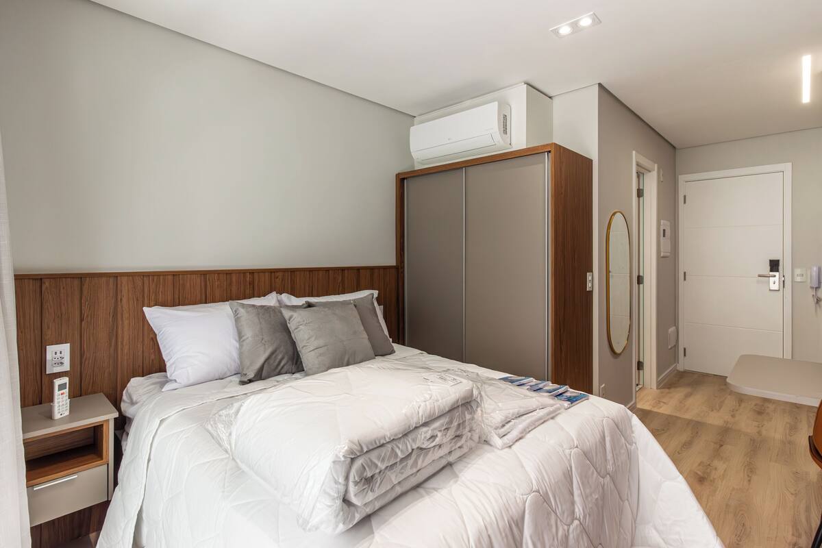 Habitación de hotel con cama, armario, mesita de noche y equipo de aire acondicionado.