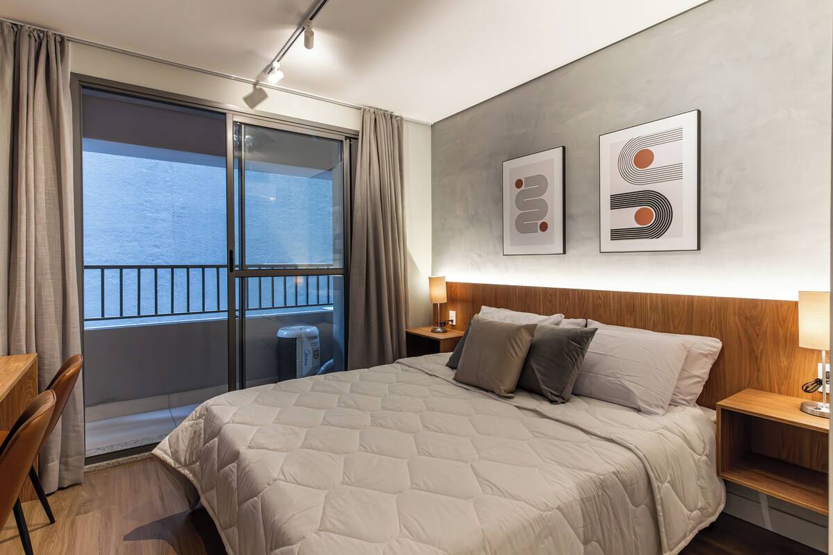 Habitación de hotel con una cama grande, cabecera de madera, un escritorio y vistas al mar a través de un ventanal corredero.