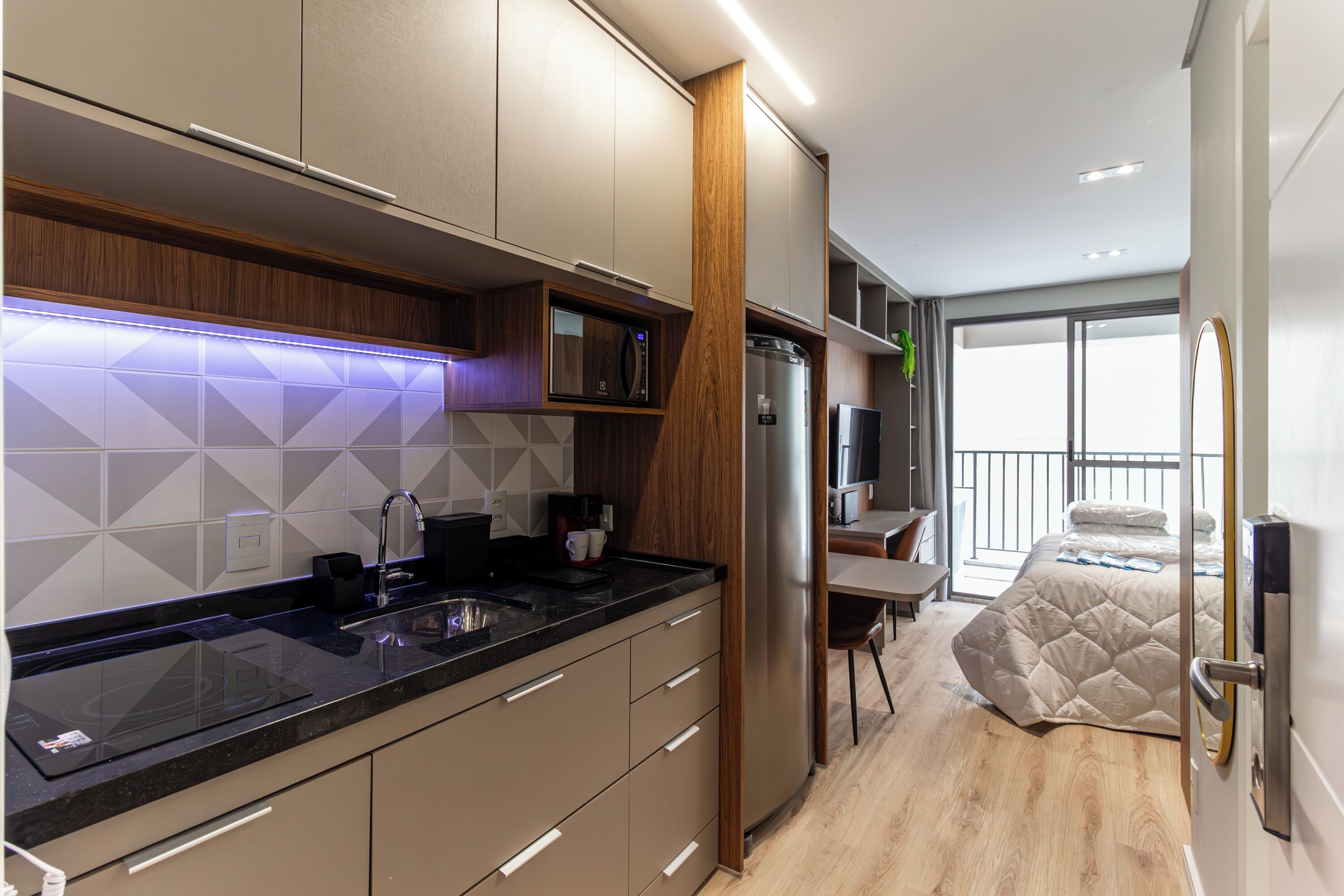 A modern kitchen with a built-in microwave, stainless steel refrigerator, and a wooden accent wall.