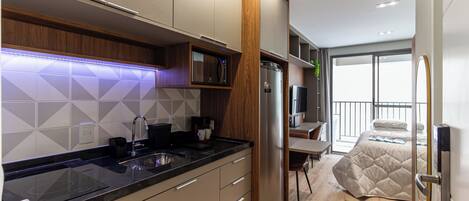 A modern kitchen with a built-in microwave, stainless steel refrigerator, and a wooden accent wall.