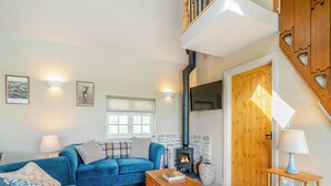 A cozy living room with a blue sofa set, a fireplace, and a wooden staircase. - 3 bedroom accommodation in Wedmore, near Glastonbury (Wedmore, near Glastonbury)