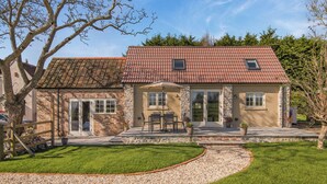 A two-story house with a red-tiled roof, stone exterior, and a patio with outdoor furniture. - 3 bedroom accommodation in Wedmore, near Glastonbury (Wedmore, near Glastonbury)