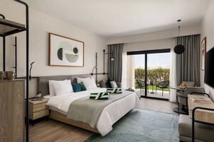 Una habitación de hotel moderna con una cama grande, un escritorio y un balcón con vistas.