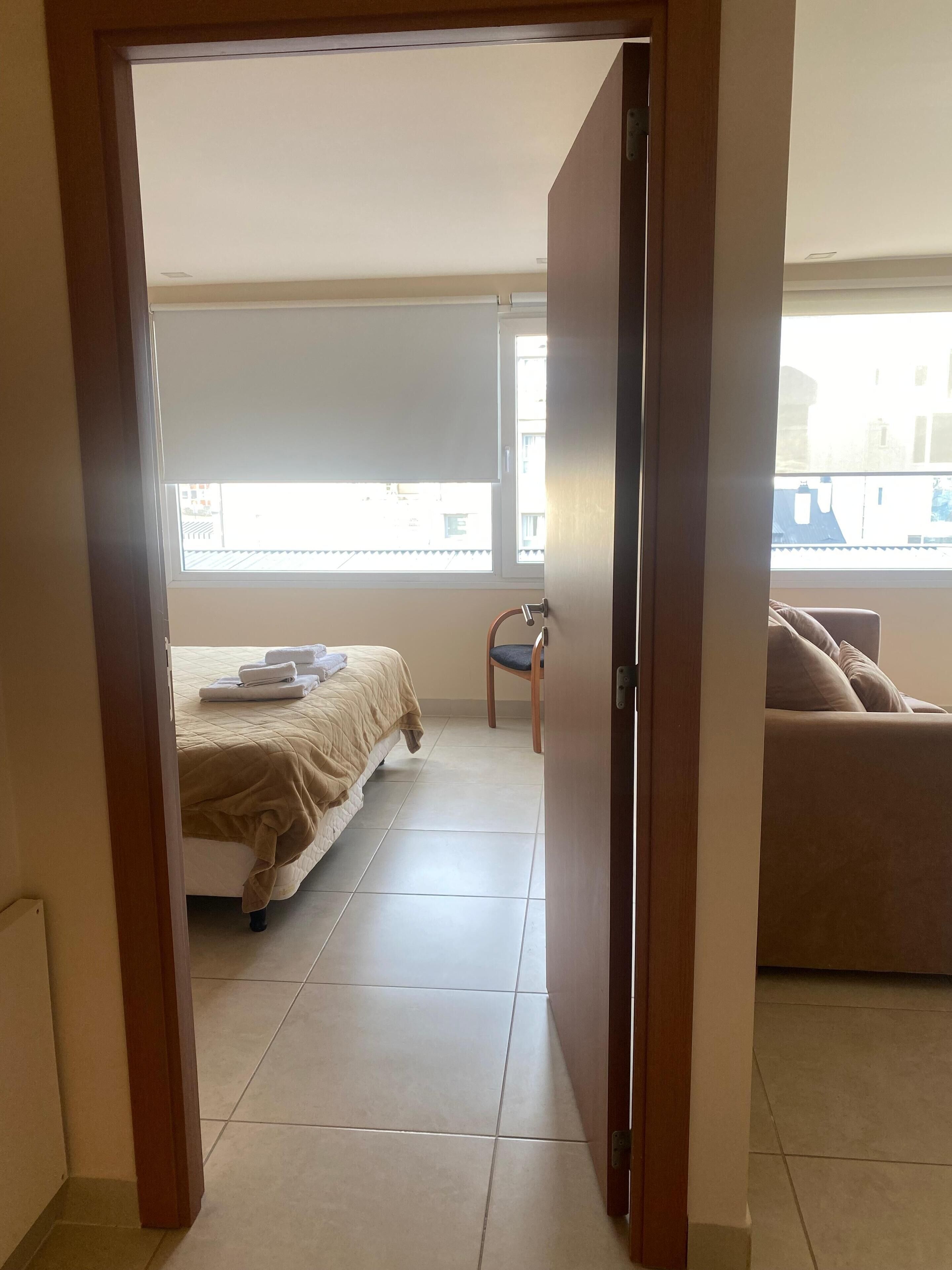 A bedroom with a bed, a chair, and a sofa.