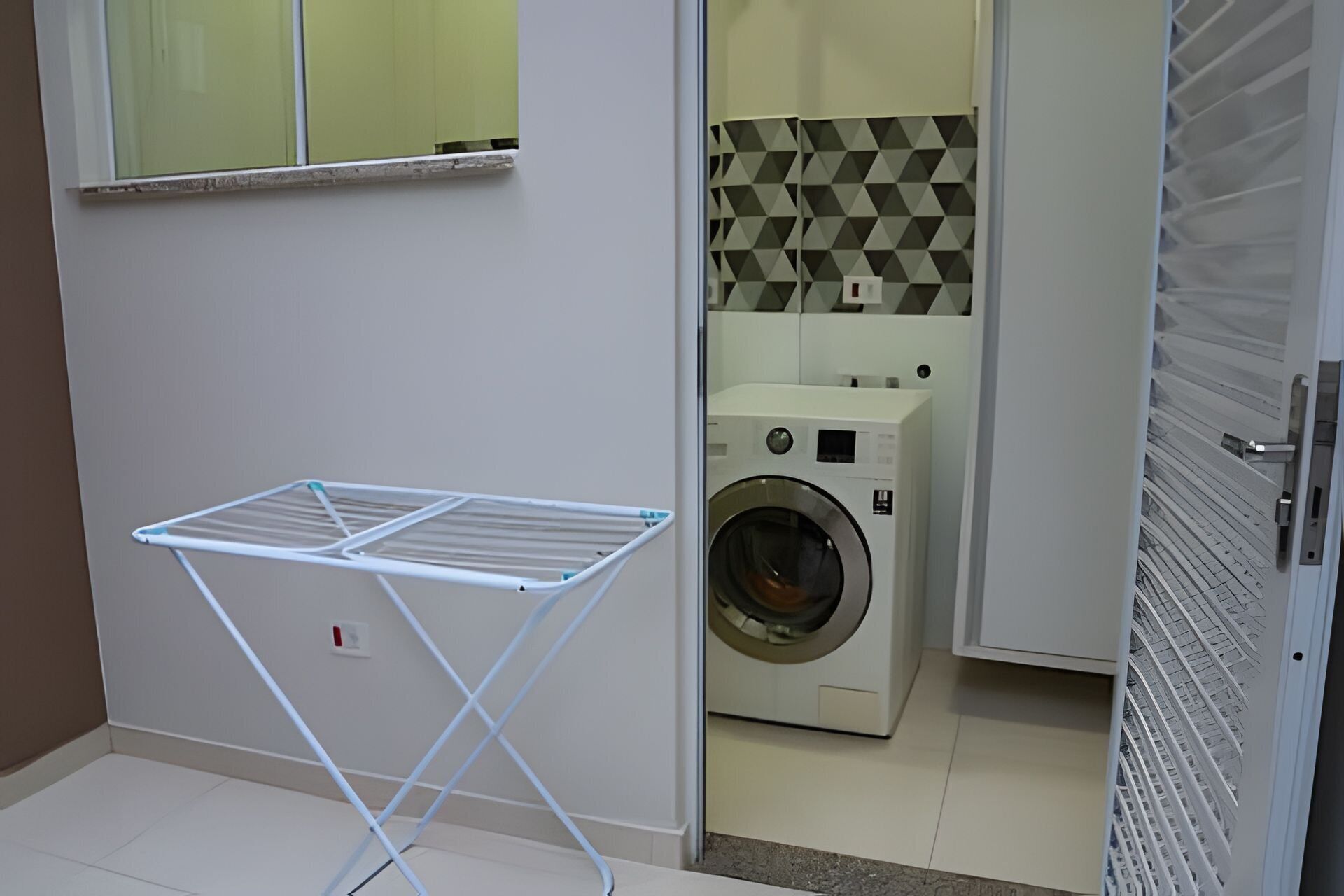 Une buanderie équipée d’un lave-linge et d’un sèche-linge, d’un étendoir et d’un sol carrelé.