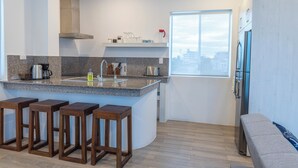 Een moderne keuken met een granieten aanrecht, roestvrijstalen apparatuur en houten barkrukken.