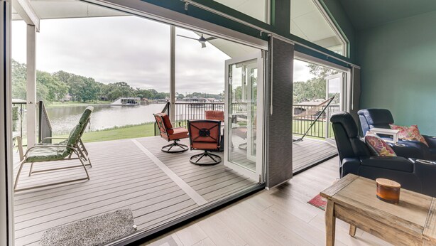 Amplio espacio interior con un gran ventanal corredero que da a una terraza con vista a un lago.